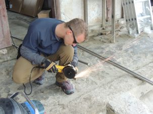 Keith cutting off the ends of the rods to make a point so we can drive them into the ground.