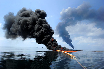 Dark clouds of smoke and fire emerge as oil burns during a controlled fire in the Gulf of Mexico, 6 May 2010. A new study found black carbon left from the burns joined a "dirty blizzard" of contaminants that eventually settled on the seafloor. Photo: U.S. Navy