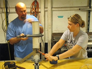 Aboard the research vessel, Steve Hovan of the Indiana University of Pennsylvania and Allison Jacobel of Lamont-Doherty Earth Observatory cut a sediment core into sections. (Pratigya Polissar/Lamont-Doherty Earth Observatory)