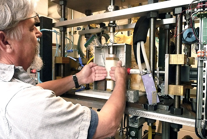 Research engineer Ted Koczynski explains how rock surfaces put pressure on a block of ice from each side as the ice is pushed downward in the new cryogenic deformation apparatus. Depending on the configuration, sensors throughout the device can measure friction, viscosity and anelasticity. Image: Lamont-Doherty Earth Observatory.